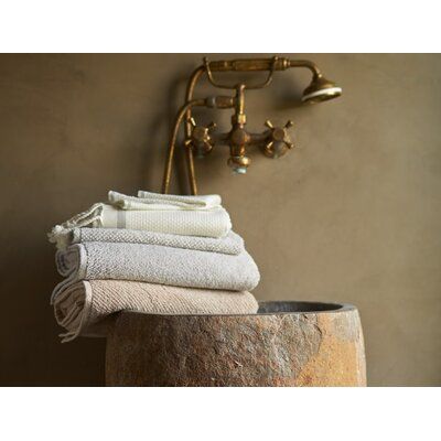 towels stacked on top of each other in front of a faucet and wall light