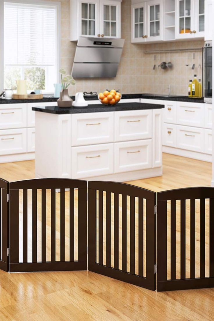 an open kitchen with white cabinets and wood flooring in the center is a dog gate that opens up to allow dogs to go inside