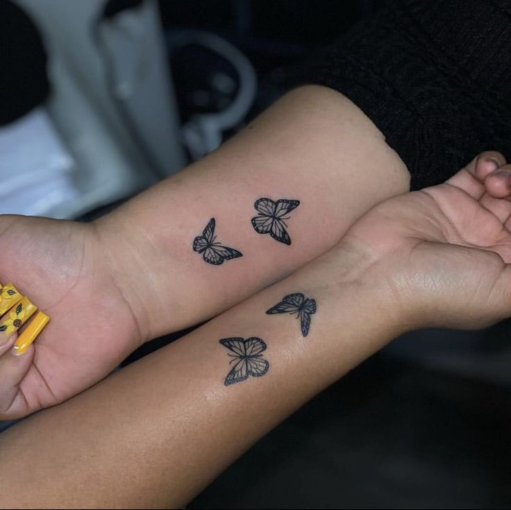 two people holding hands with tattoos on their arms and one has a yellow object in the other hand