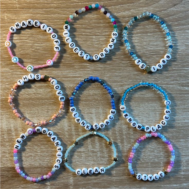 six bracelets with white and blue beads are arranged on a wooden surface, one has an evil eye