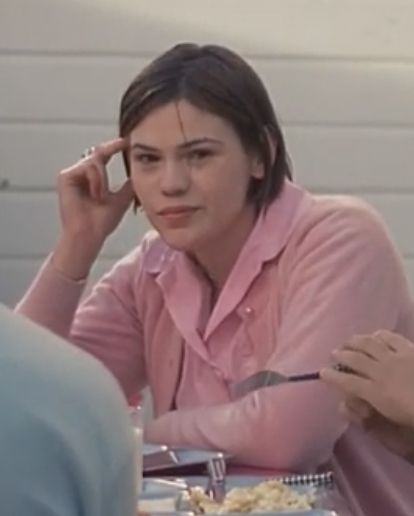 a woman sitting at a table with food in front of her and two other people