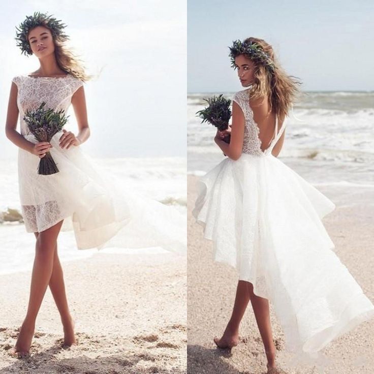 two women in white dresses on the beach, one wearing a flower crown and the other with flowers in her hair