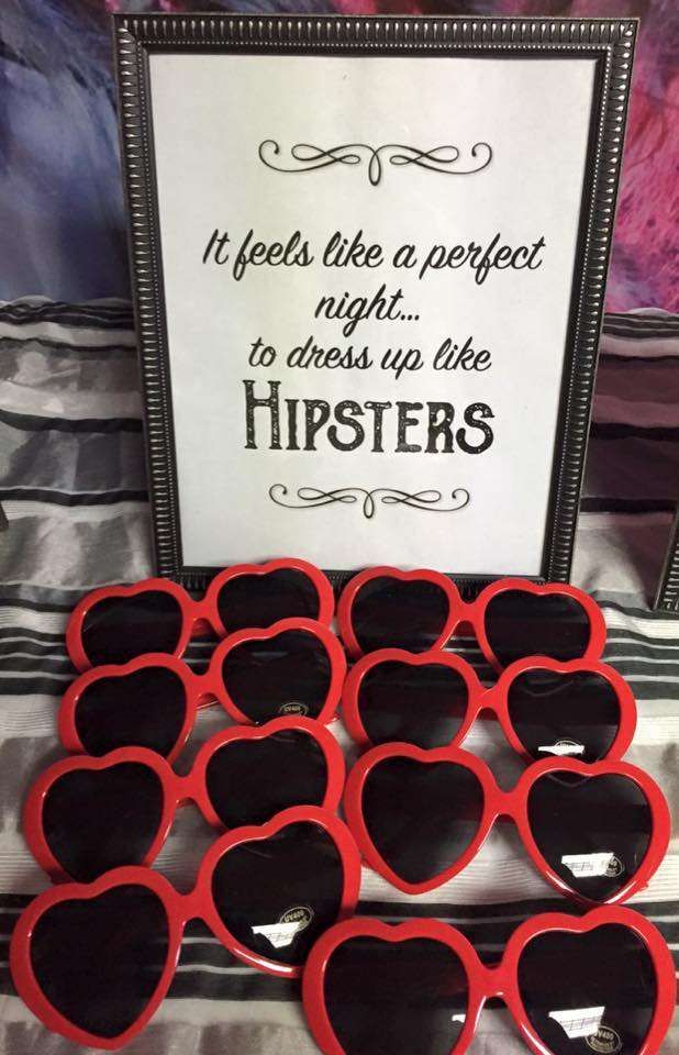 red heart shaped sunglasses sitting on top of a table next to a sign that says it feels like a perfect night to dress up like hipsters