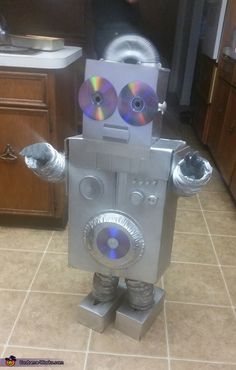 a robot that is standing in the kitchen with cds on his head and hands out
