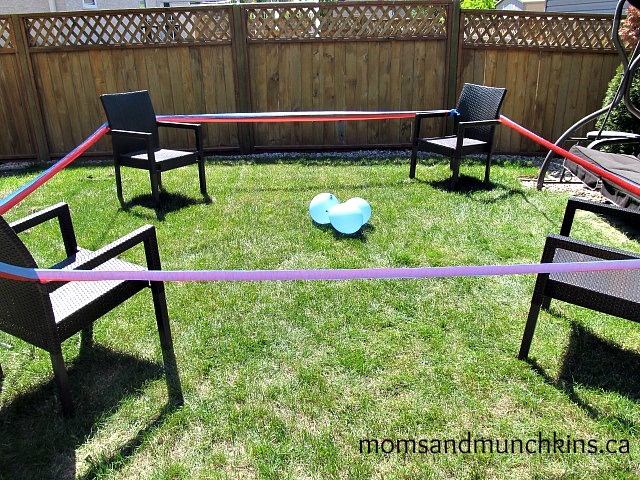 an empty lawn with chairs and a ball on the ground in front of a fence