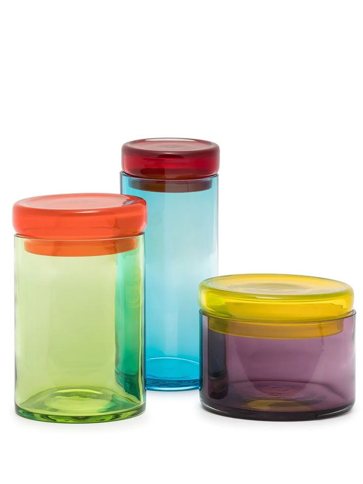 three different colored glass containers sitting next to each other
