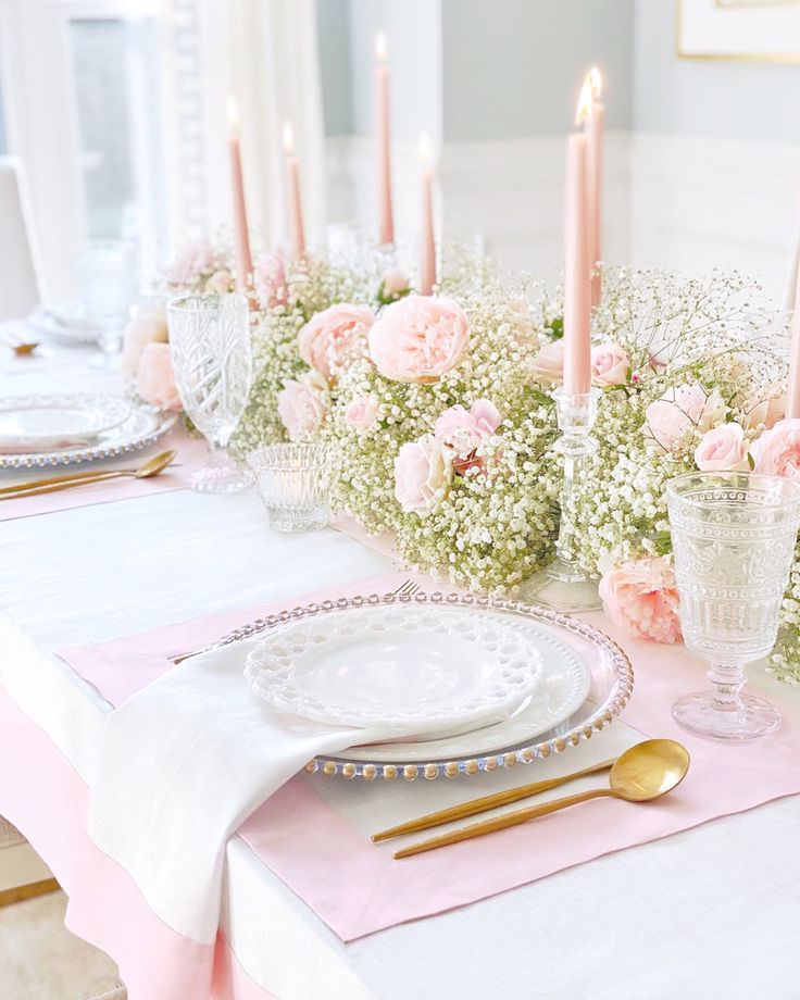 the table is set with pink flowers and candles