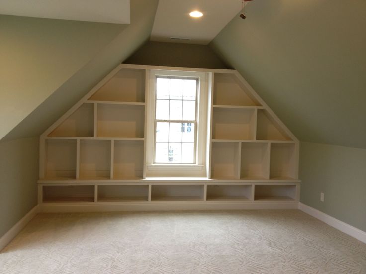 an empty room with shelves and a window in the corner on the far wall is a carpeted floor