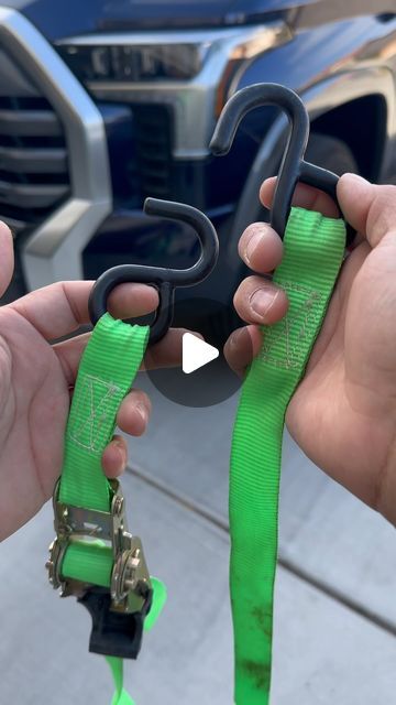 two hands holding green ribbon and scissors in front of a truck with it's hood open