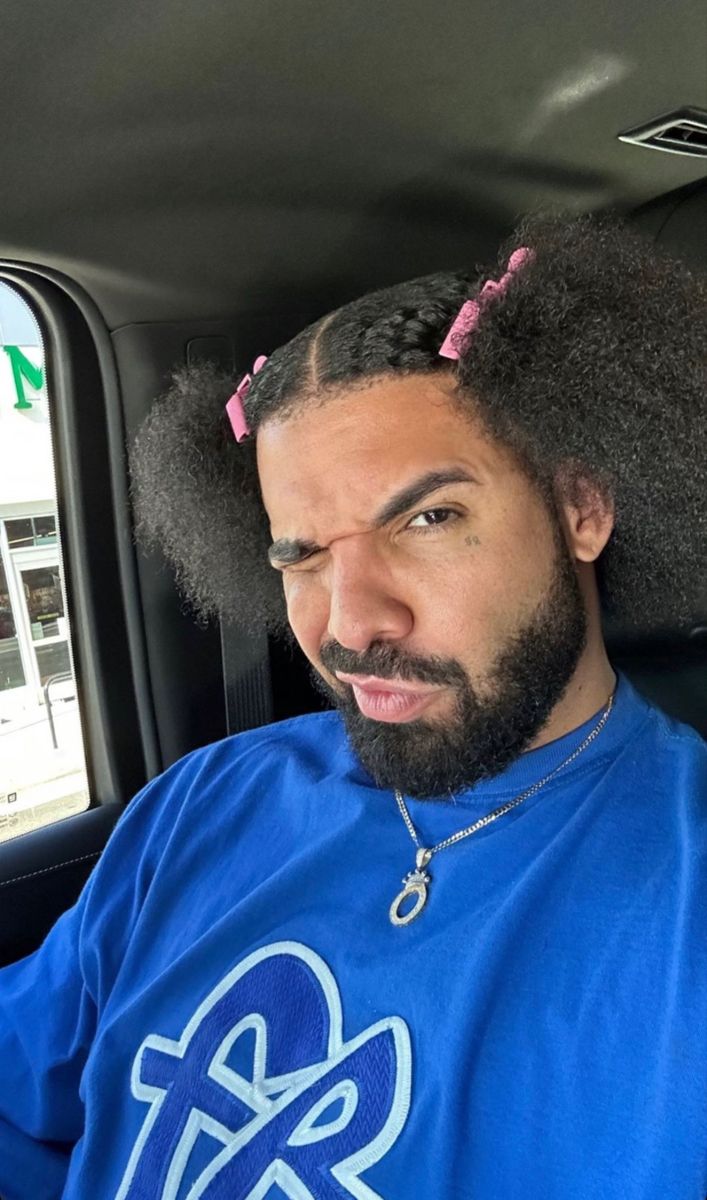 a man sitting in the back seat of a car with an afro on his head