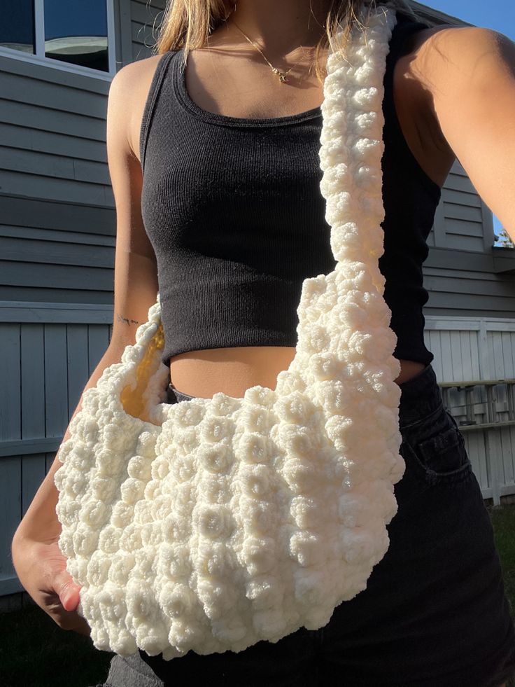 a woman holding a white crocheted purse