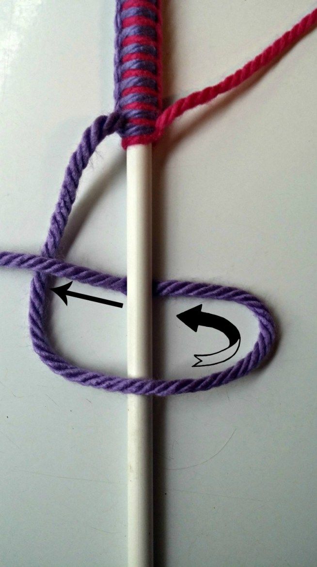 a close up of a crochet hook on a white surface with purple and pink yarn