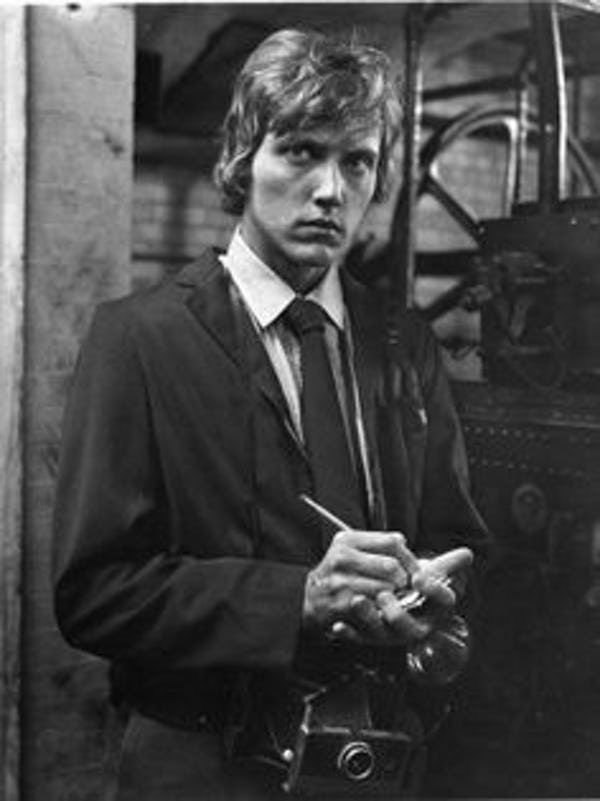 black and white photograph of man in suit holding camera