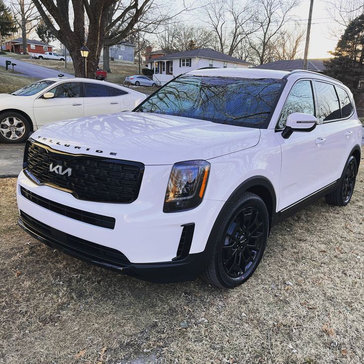 a white suv parked in front of some trees