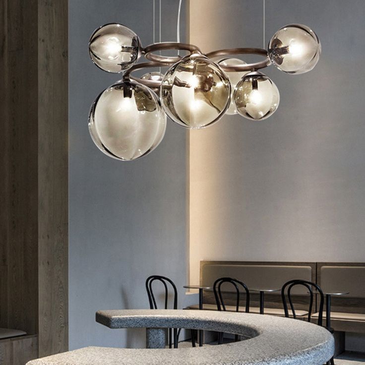 a modern chandelier hanging over a table in a room with chairs and tables