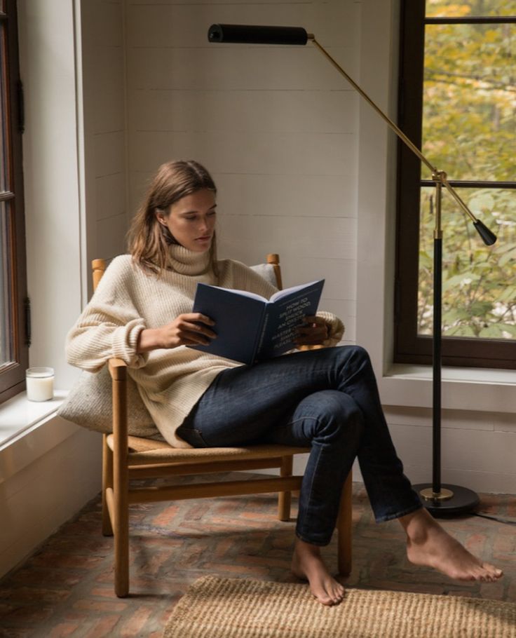 a woman sitting in a chair reading a book