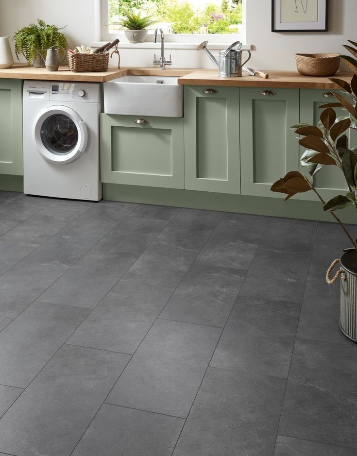 a kitchen with grey tile floors and green cabinets, white washer and dryer on the counter