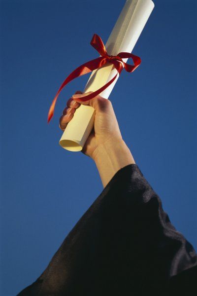 a person holding up a diploma in the air with a red ribbon on it's end