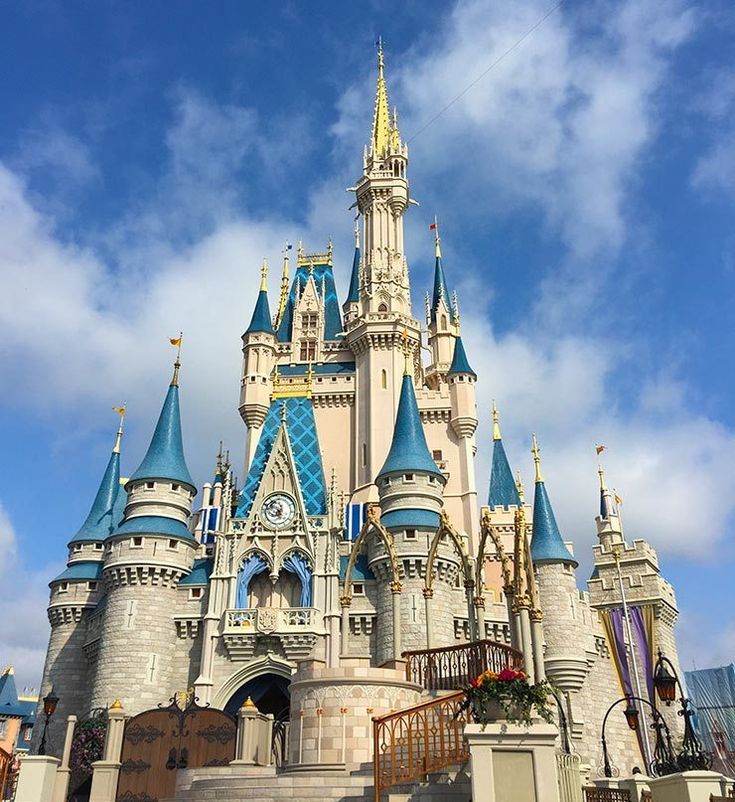 a large castle with many towers and blue roofing on it's sides, in front of a cloudy sky