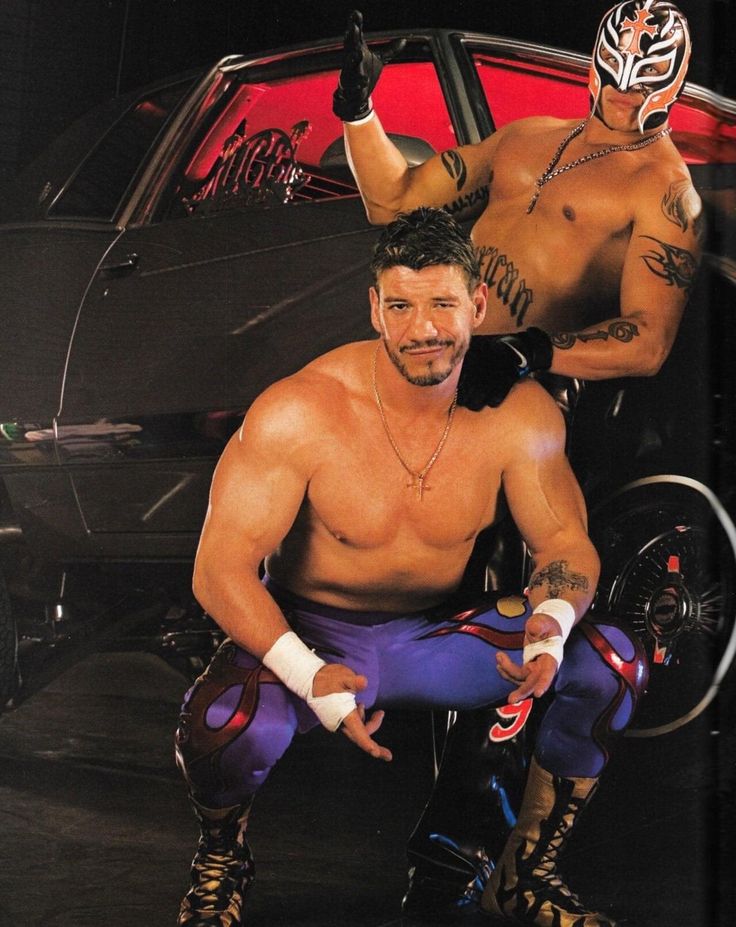 two men in wrestling gear sitting next to each other with their hands on their hipss
