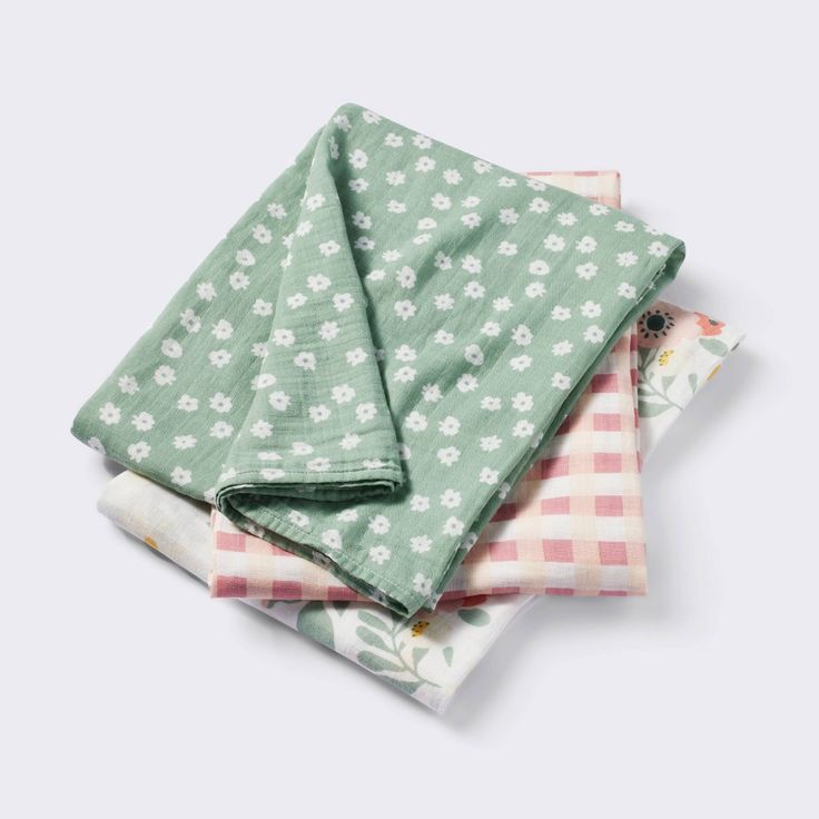 four napkins with flowers and gingham checks on the bottom, one in green