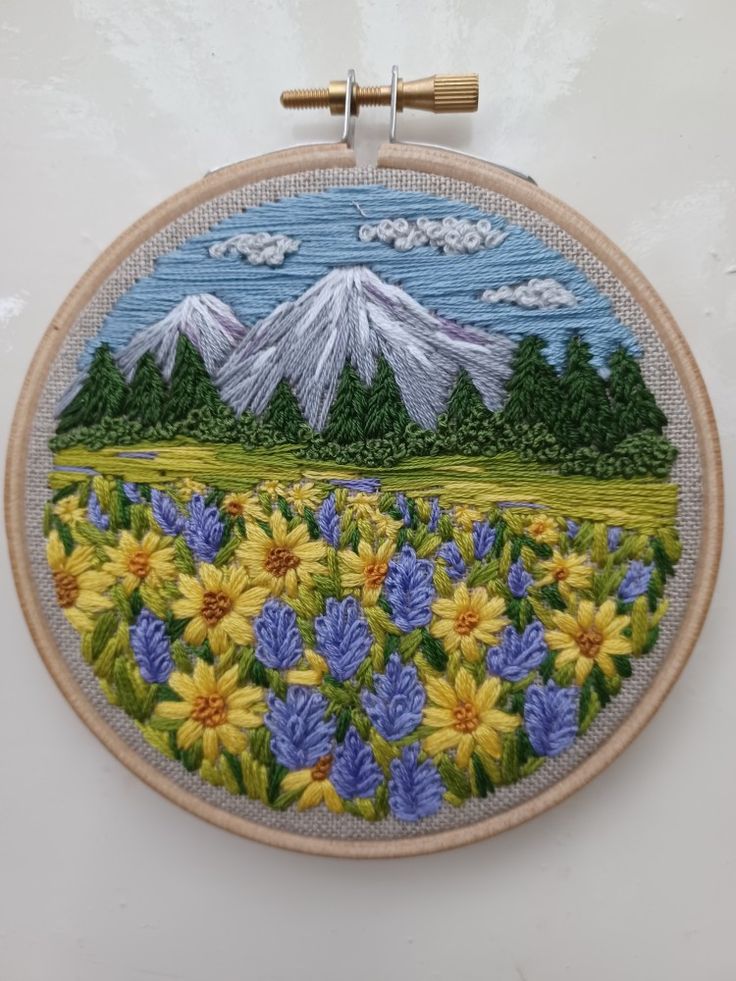 an embroidery project with flowers and mountains in the background