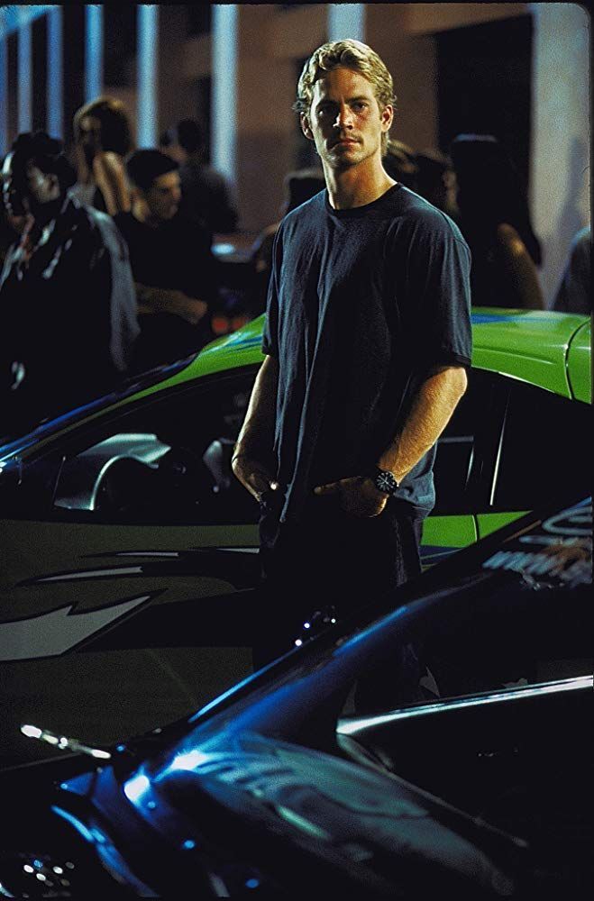 a man is standing in front of some cars and looking at the camera with his hands on his hips