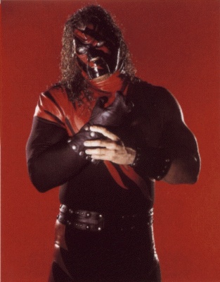 a man with long hair wearing a leather outfit and holding his hands on his chest