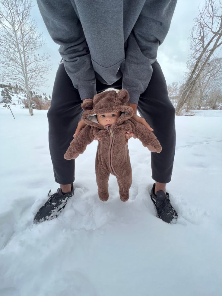a person standing in the snow with a stuffed animal