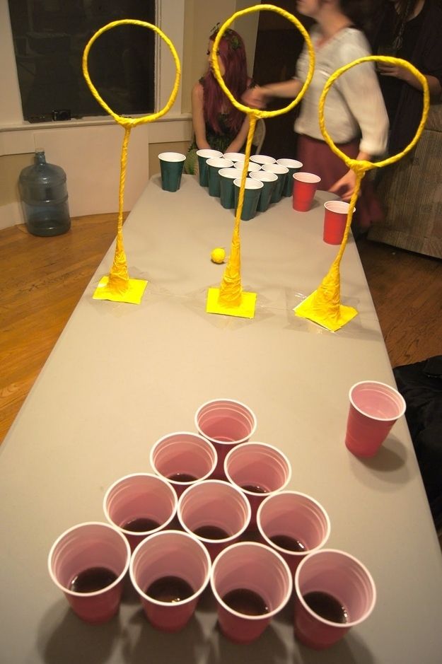 a table with cups on it and some people in the background playing ping pong