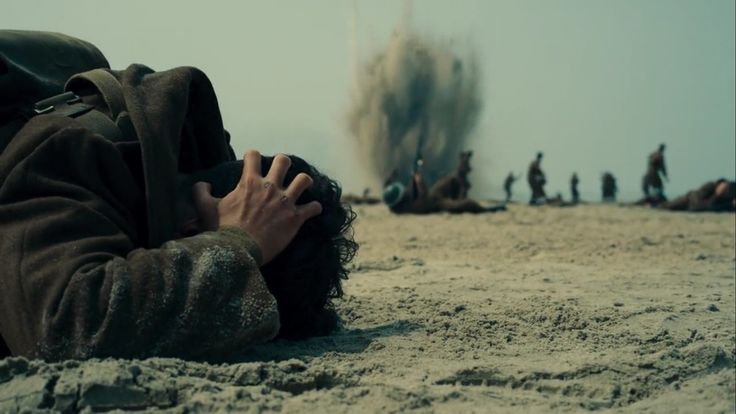 a man laying in the sand with his head on his hands