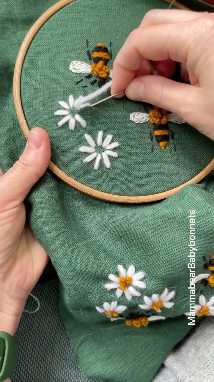 a person is stitching flowers on a green cloth