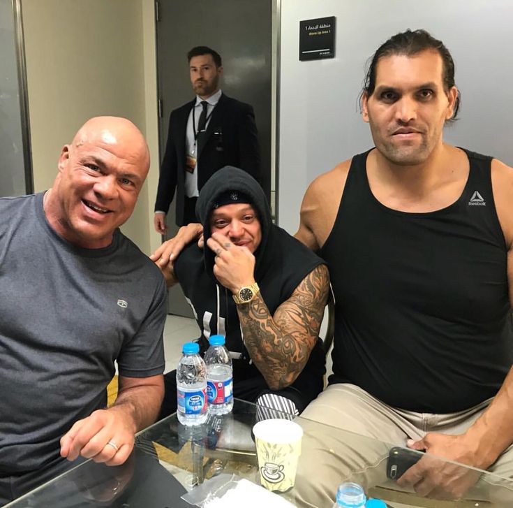 two men sitting next to each other in front of a table with water bottles on it