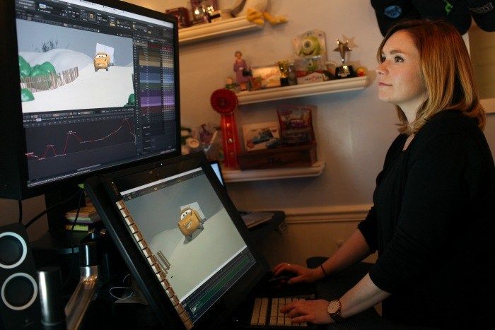 a woman sitting in front of a computer monitor with an owl on it's screen