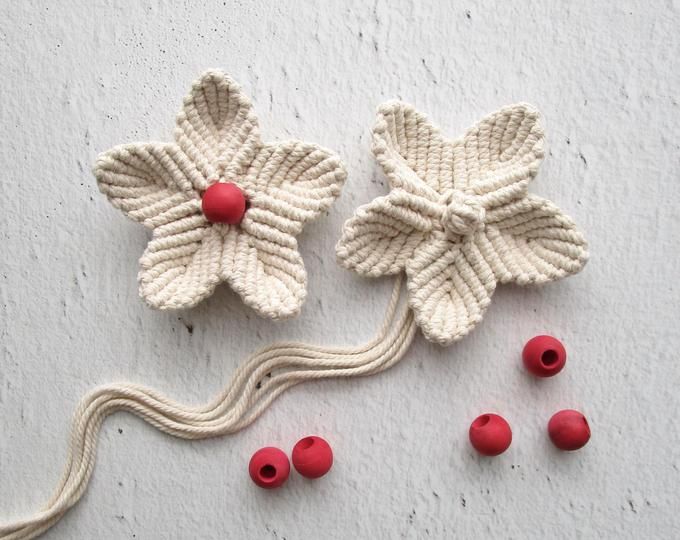 two crocheted flowers with red beads on the bottom and white yarn in the middle