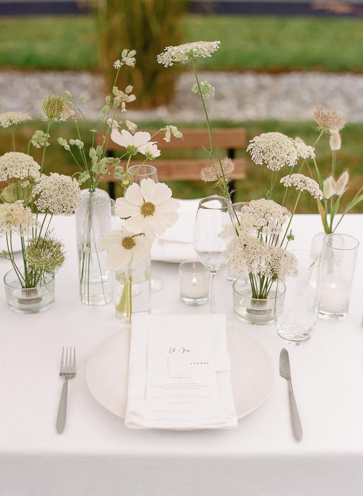 the table is set with white flowers and silverware