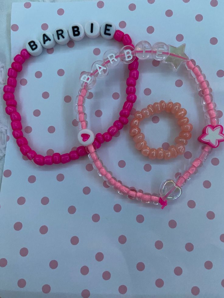 two bracelets with name beads on them sitting on top of a polka dot table