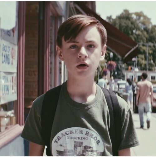 a young boy standing in front of a store with his mouth open and looking at the camera