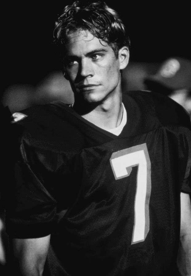 a black and white photo of a young man wearing a football uniform with the number seven on it