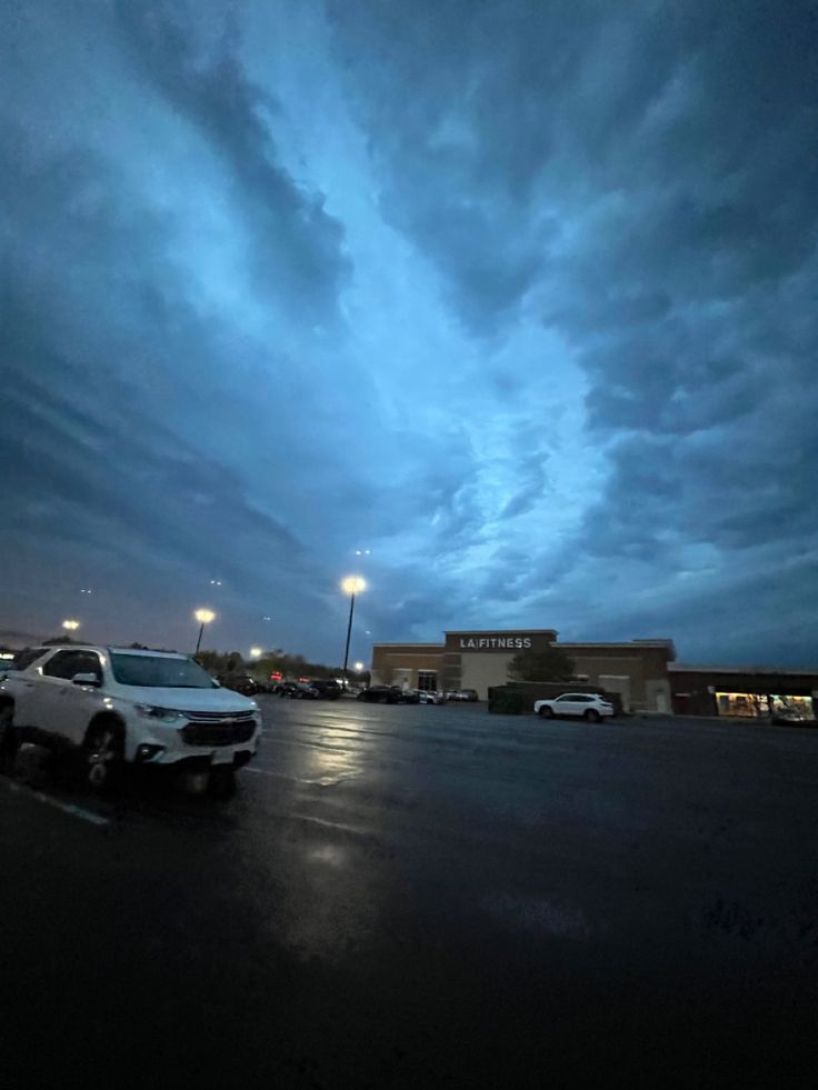 cars are parked in a parking lot at night with the sky covered in dark clouds