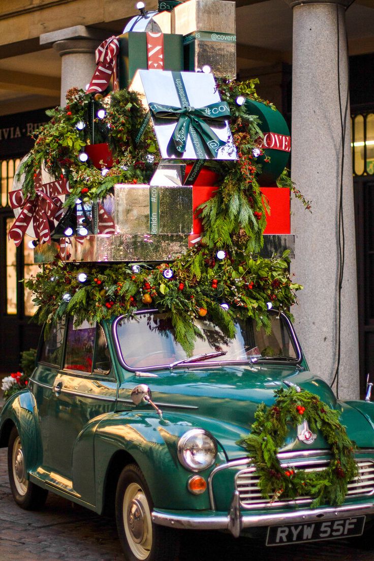 an old green car with christmas decorations on the roof and presents tied to it's roof