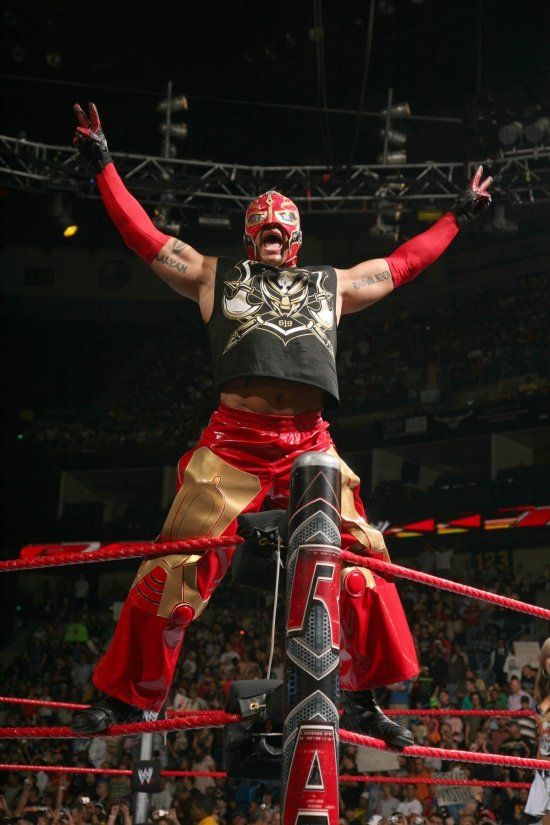 a wrestler is standing on top of a rope in the middle of a wrestling ring