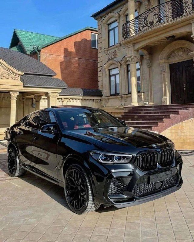 a black bmw x5 parked in front of a large building with steps leading up to it