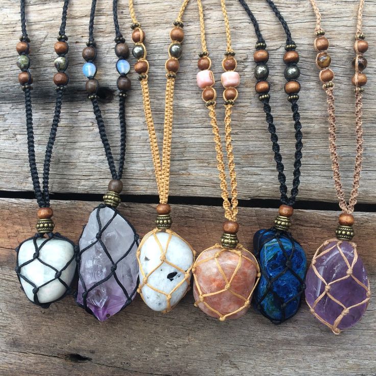 six different necklaces are hanging on a wooden surface with beaded cord and beads