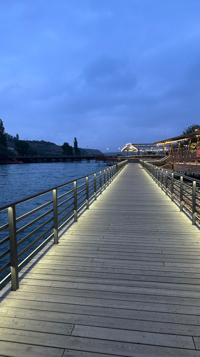 a long wooden pier with lights on it's sides