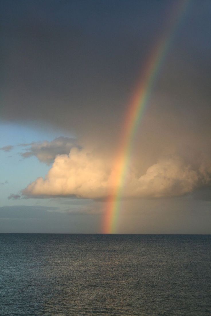 a rainbow is shining in the sky over the ocean