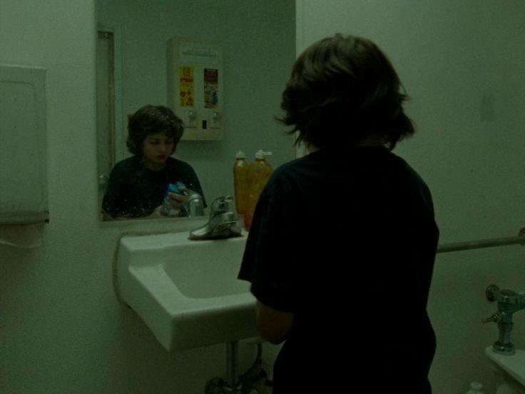 two people standing in front of a bathroom mirror looking at each other's reflection