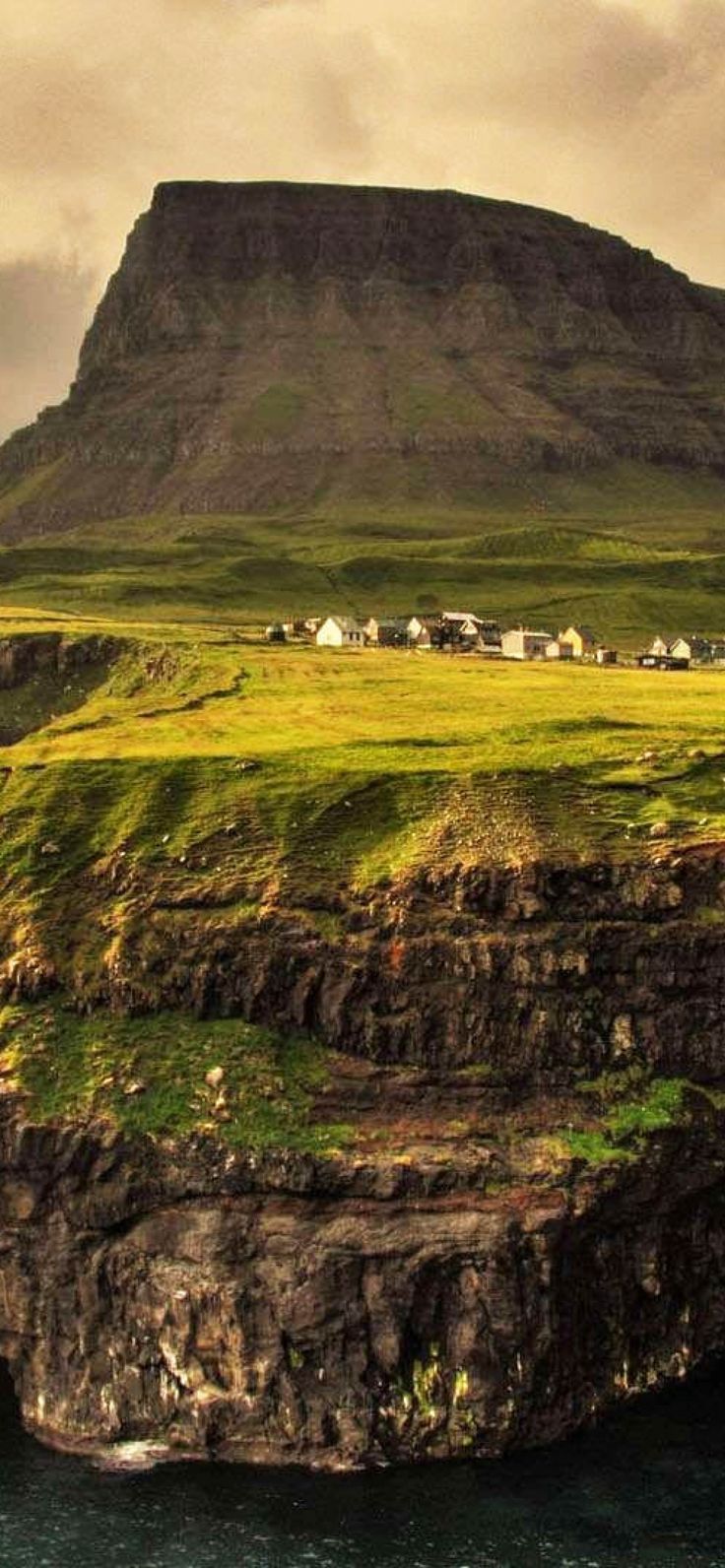 an island sits on the edge of a body of water in front of a mountain