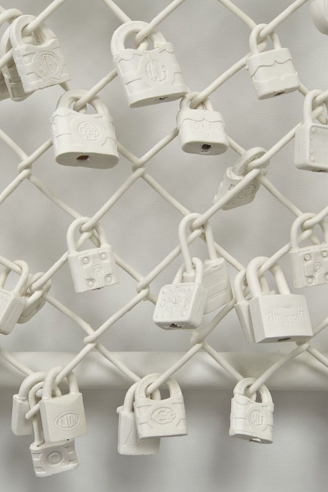 many padlocks are attached to a chain link fence with white locks on them