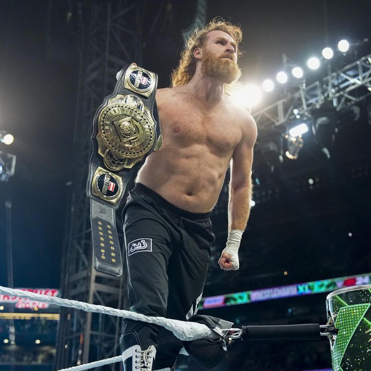 a man standing on top of a wrestling ring holding a belt in one hand and looking up at the sky